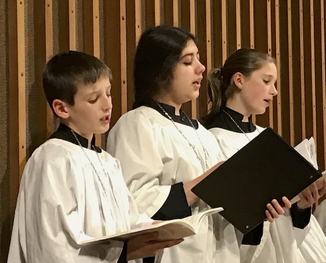 Children and youth celebrate Pentecost inside the Trinity sanctuary, red petals flying beneath the Kepes window
