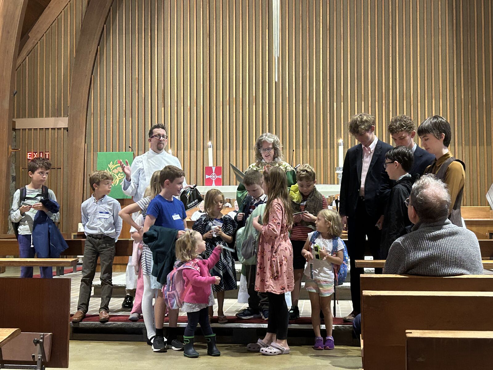 Children with their backpacks gathered at the altar with the priest for the Blessing of the Backpacks